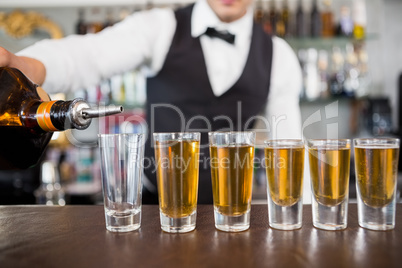 Waiter making shots at bar counter