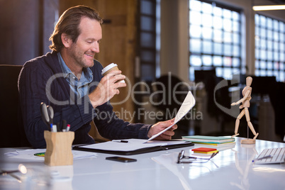 Businessman having coffee while reading document