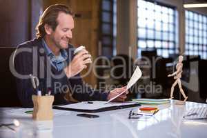 Businessman having coffee while reading document