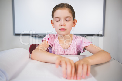 Schoolgirl reading a braille book in classroom