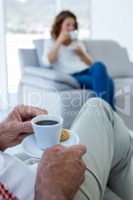 Low section of man having coffee with woman at home