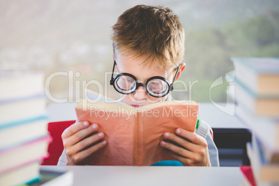 Close-up of schoolkid reading book in classroom