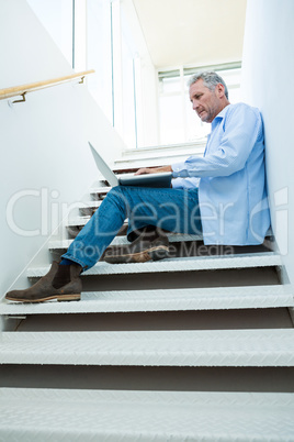 Focused man using laptop on steps Focused man using laptop on steps