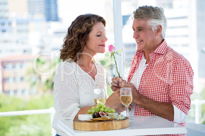 Mature woman with man smelling flower