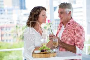 Mature woman with man smelling flower