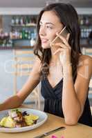Woman talking on mobile phone while having meal