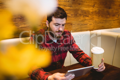 Young man using digital tablet at table in restaurant