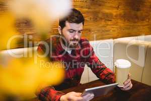 Young man using digital tablet at table in restaurant