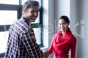 Young colleagues shaking hands in office