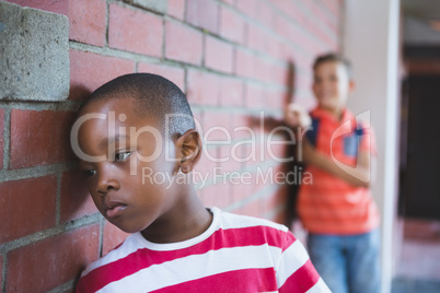 Schoolkid bullying a sad boy in corridor