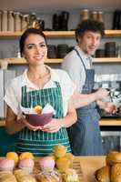 Waitress holding bowl with snack while waiter using coffee machi