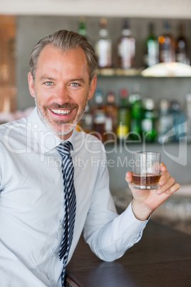 Happy man holding a glass of whiskey