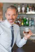 Happy man holding a glass of whiskey