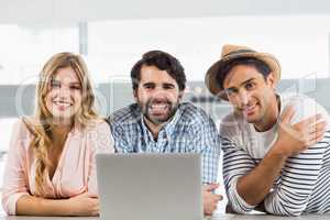Portrait of smiling woman and two men using laptop