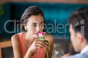 Woman smelling a rose offered by man