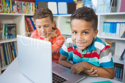 School kids using a laptop in library