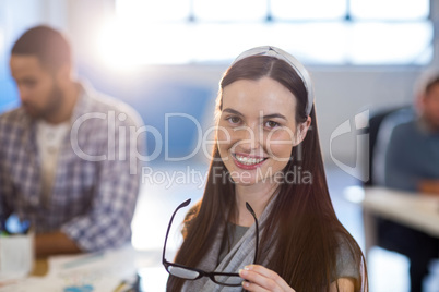 Smiling businesswoman holding eyeglasses at office