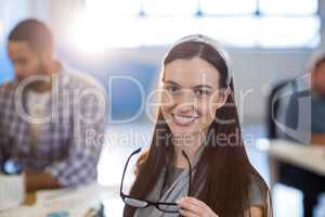 Smiling businesswoman holding eyeglasses at office