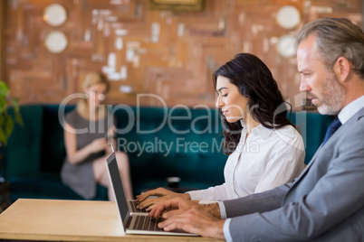 Business colleagues sitting on table and using laptop