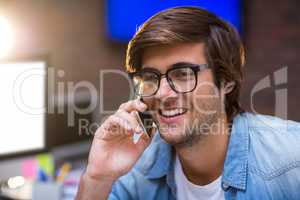 Smiling young man talking on phone in office