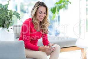 Woman using cellphone while relaxing on couch