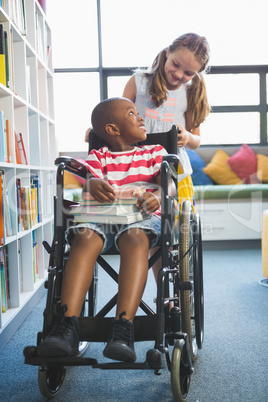 Happy schoolgirl carrying schoolboy in wheelchair