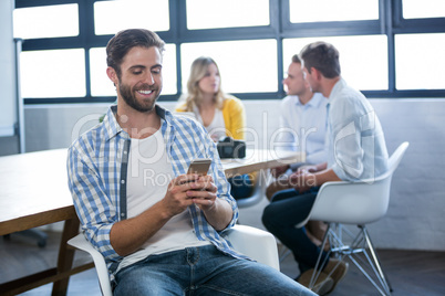 Creative businessman using cellphone by table