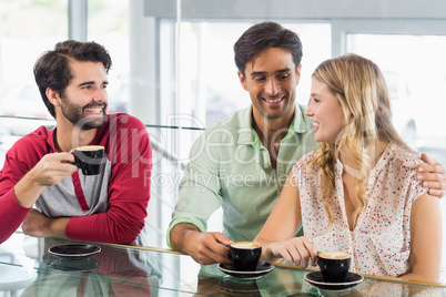 Smiling woman and two men having cup of coffee