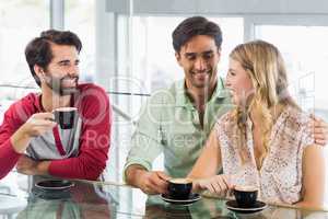 Smiling woman and two men having cup of coffee