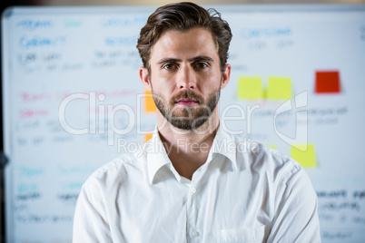 Confident businessman standing against whiteboard