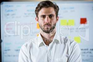 Confident businessman standing against whiteboard