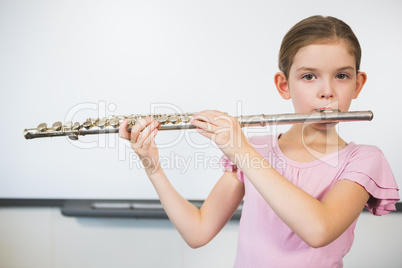 Portrait of schoolgirl playing flute in classroom