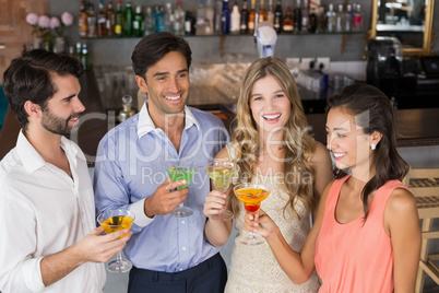 Happy friends holding cocktail glasses