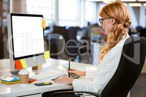 Businesswoman using graphics tablet at desk