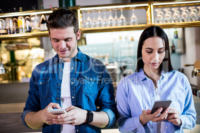 Man and woman using cellphone in bar