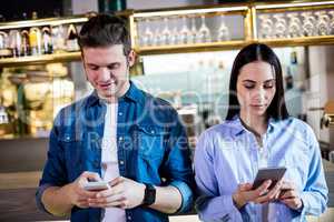 Man and woman using cellphone in bar