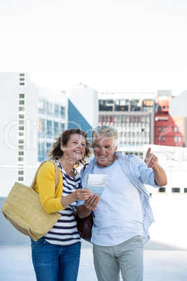 Smiling couple holding map in city