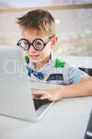 Close-up of schoolkid using laptop in classroom