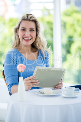 Portrait of smiling mature woman holdingdigital tablet