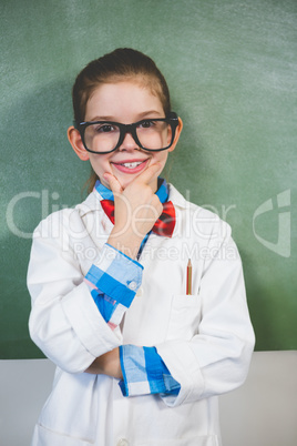 Portrait of smiling girl standing with hand on chin in classroom