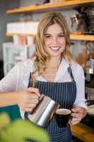 Portrait of smiling waitress making cup of coffee