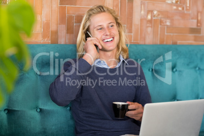 Man having cup of coffee while talking on the phone