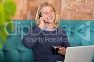 Man having cup of coffee while talking on the phone