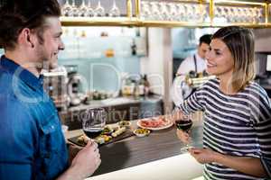 Couple smiling while having wine by counter