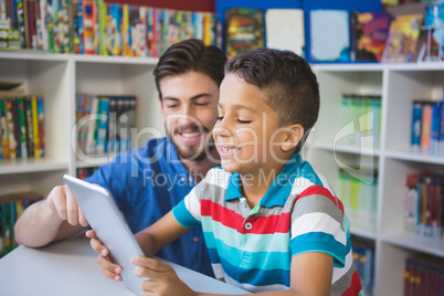 Teacher and school kid using digital table in library