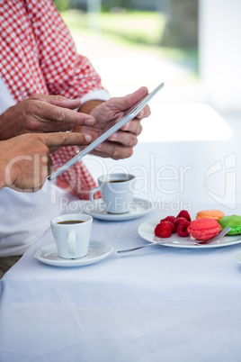 Midsection of man with friend using digital tablet