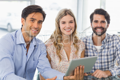 Portrait of smiling woman and two men using digital tablet