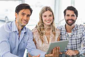 Portrait of smiling woman and two men using digital tablet