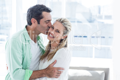 Mid adult man kissing woman at home