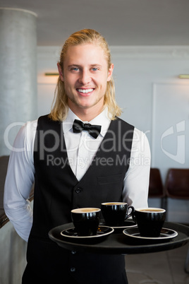 Waiter holding a tray with coffee cups in restaurant
